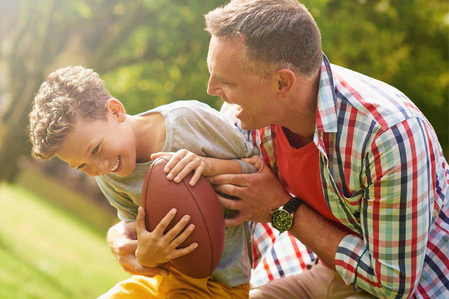 adult playing football with child